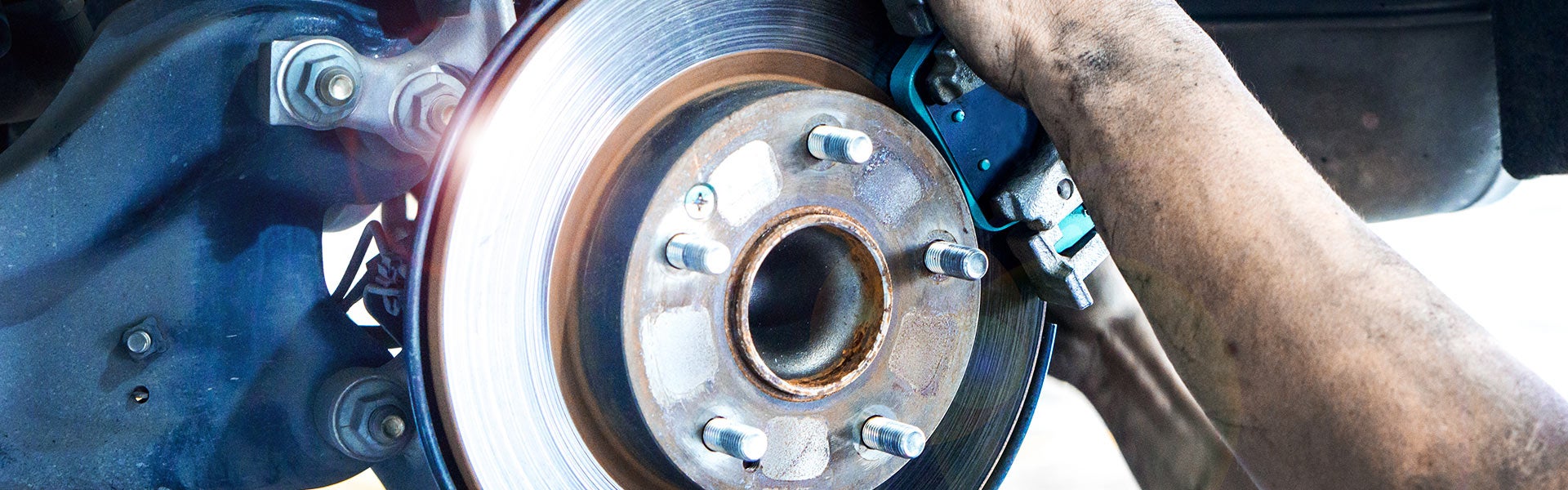 A mechanic performing a brake inspection or service on a vehicle's disc brake rotor and caliper assembly.